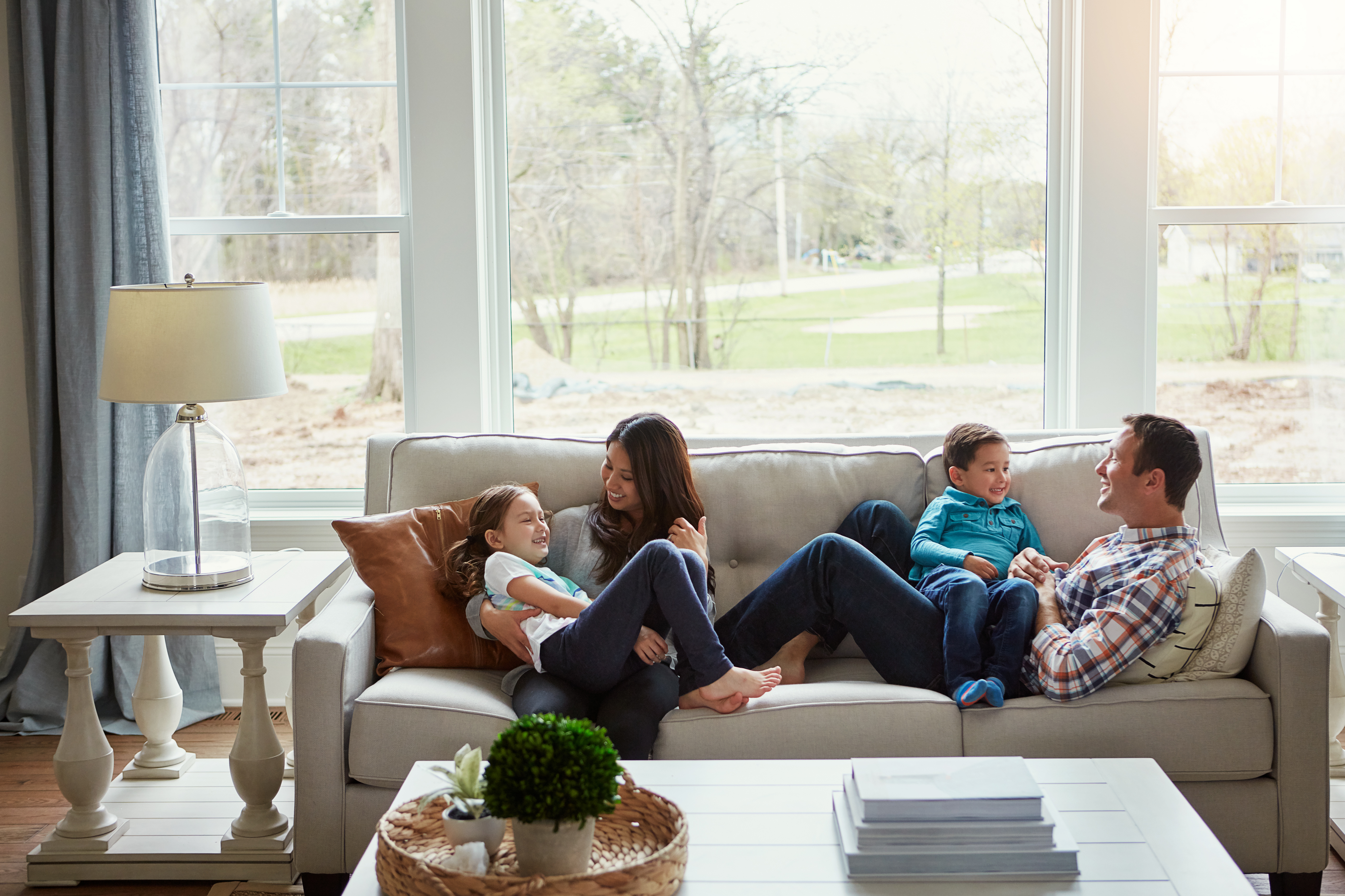 A happy family of four relaxing together on the sofa at home.