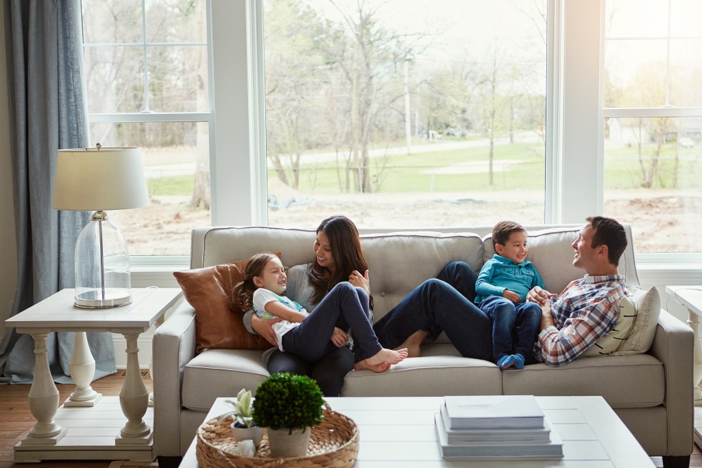 A happy family of four relaxing together on the sofa at home.