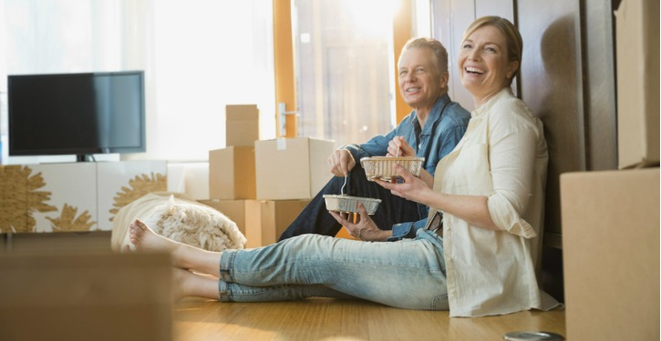 Couple Sitting on Floor Resting and Eating During Moving Into New Home