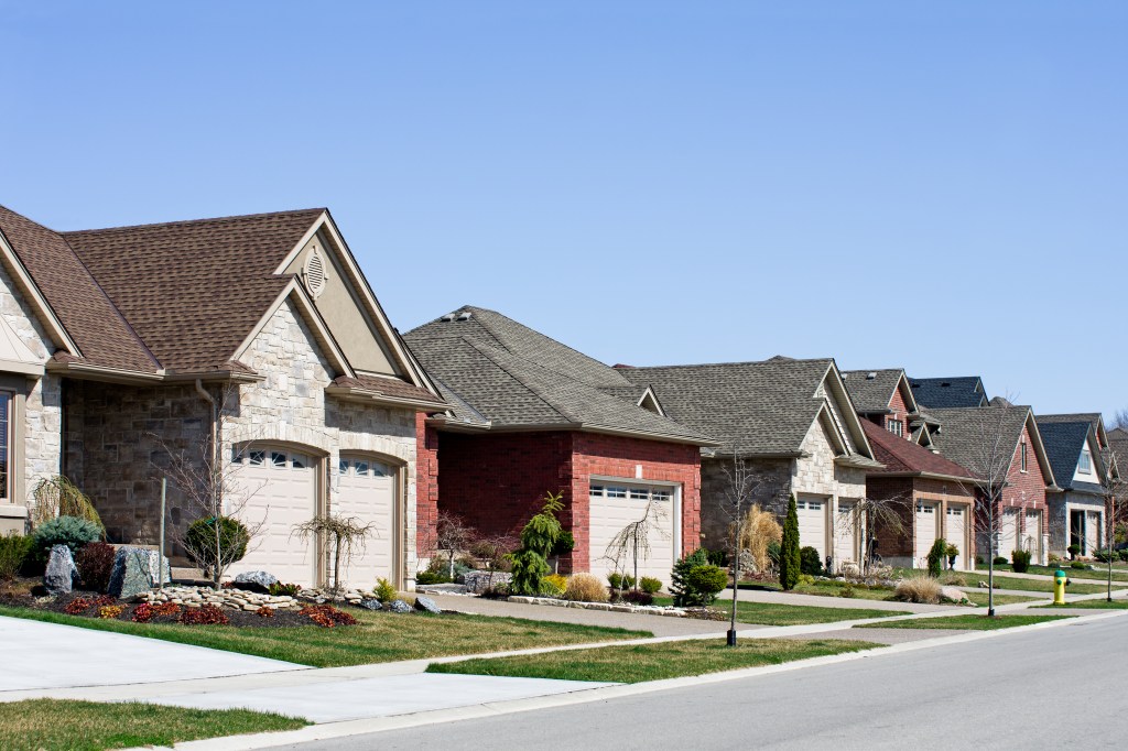 View down a residential suburban street in spring with a variety of middle-class bungalows. Residential row house background image.
