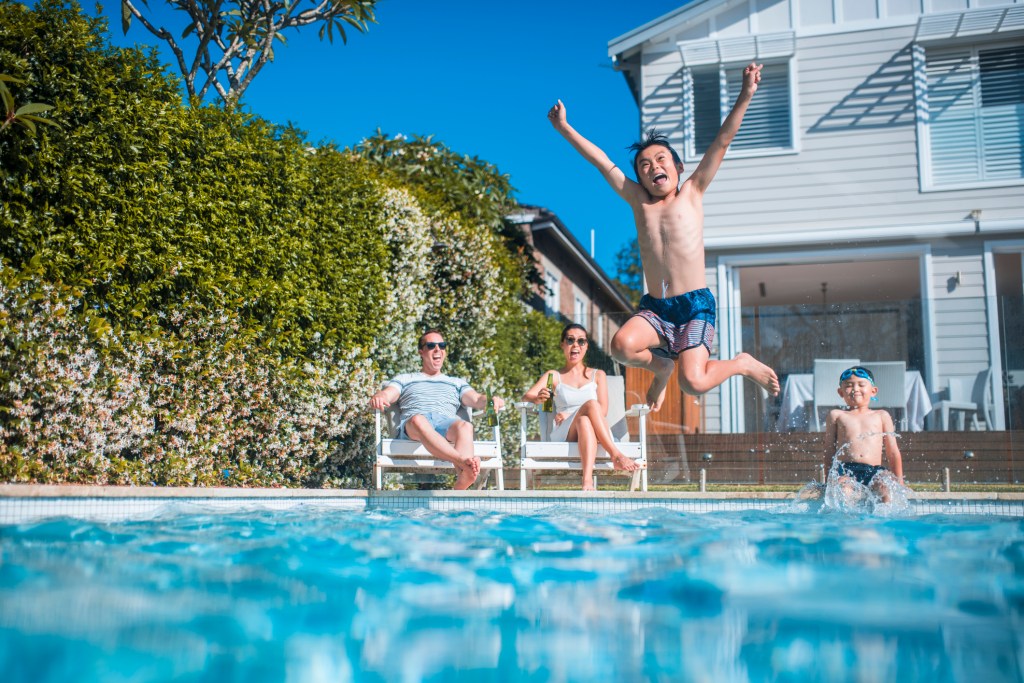 Family having fun in the backyard. Kids are swimming.