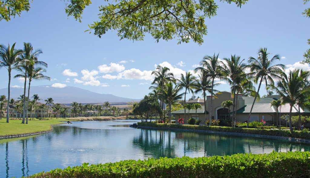 Housing community surrounded by a lake with mountain views.