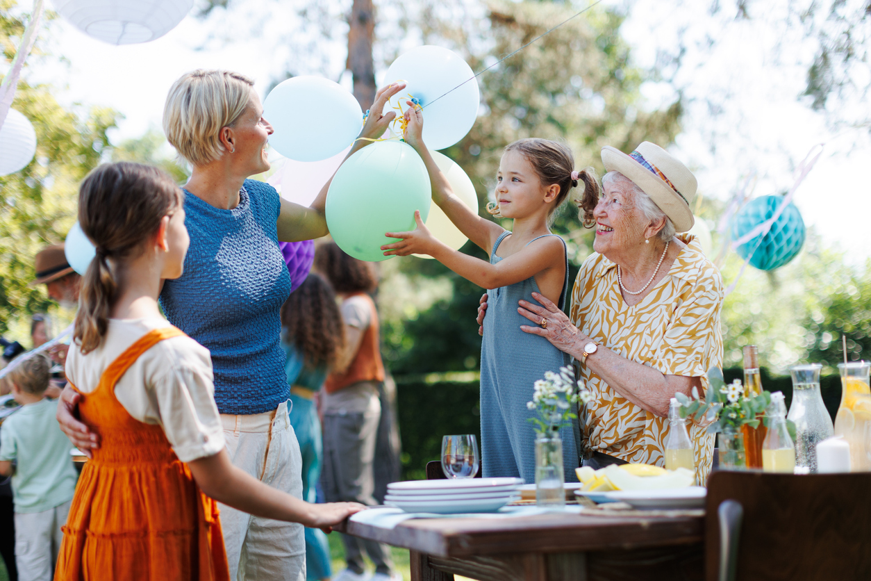 Grandmother, mother and daughter setting decorations for summer garden party.