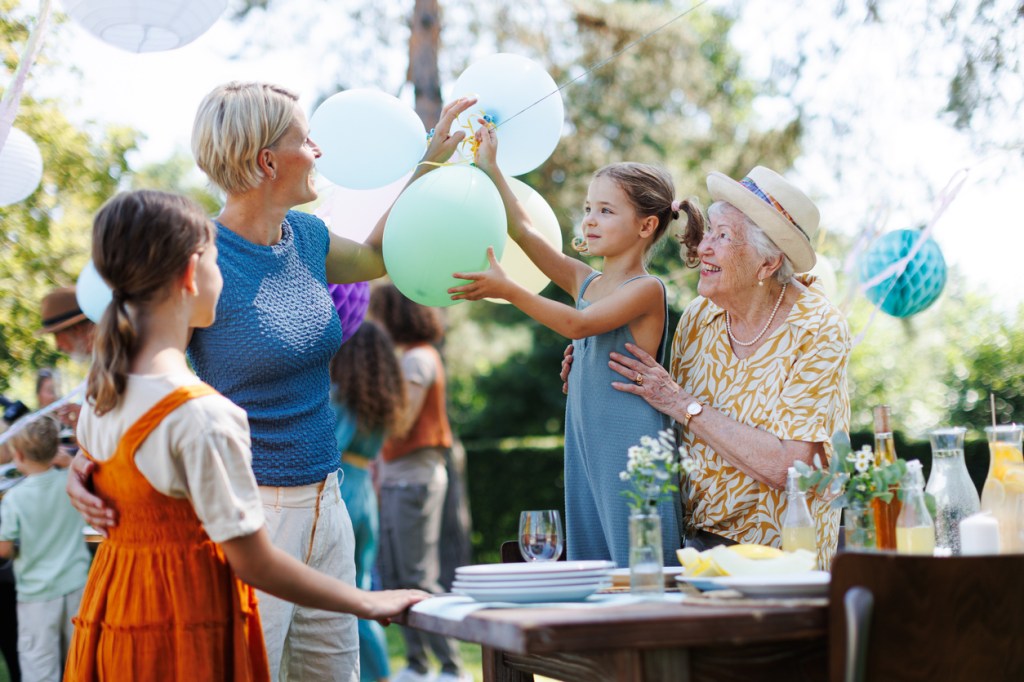 Grandmother, mother and daughter setting decorations for summer garden party.