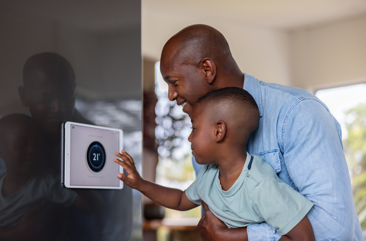 Father and son using a home automation system to lower the temperature of their house.