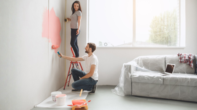 Happy couple painting their living room.