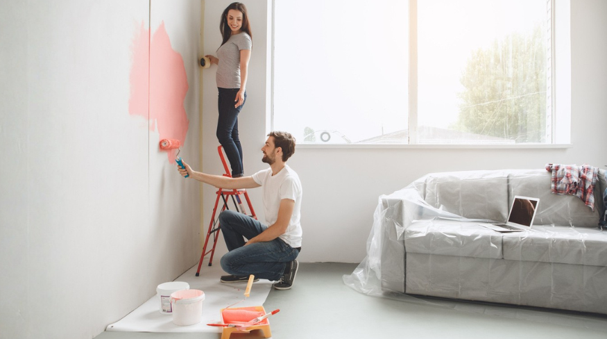 Happy couple painting their living room.