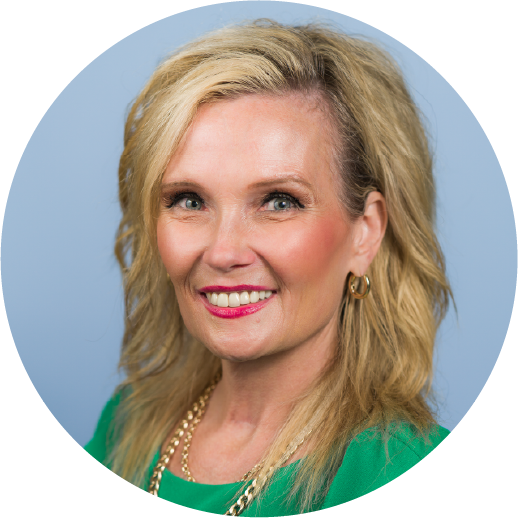 Professional headshot: smiling blonde woman wearing a green top and gold jewelry against a light blue background.